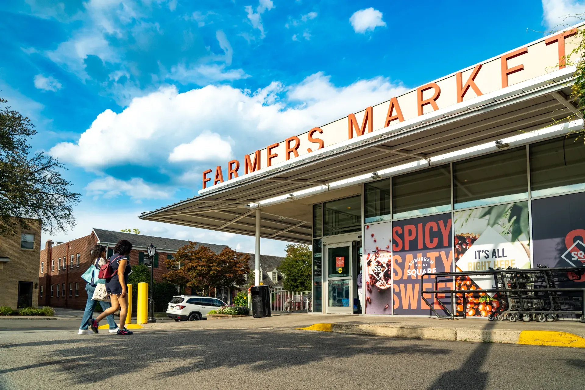 Two women walking into the well-stocked farmers market at Suburban Square