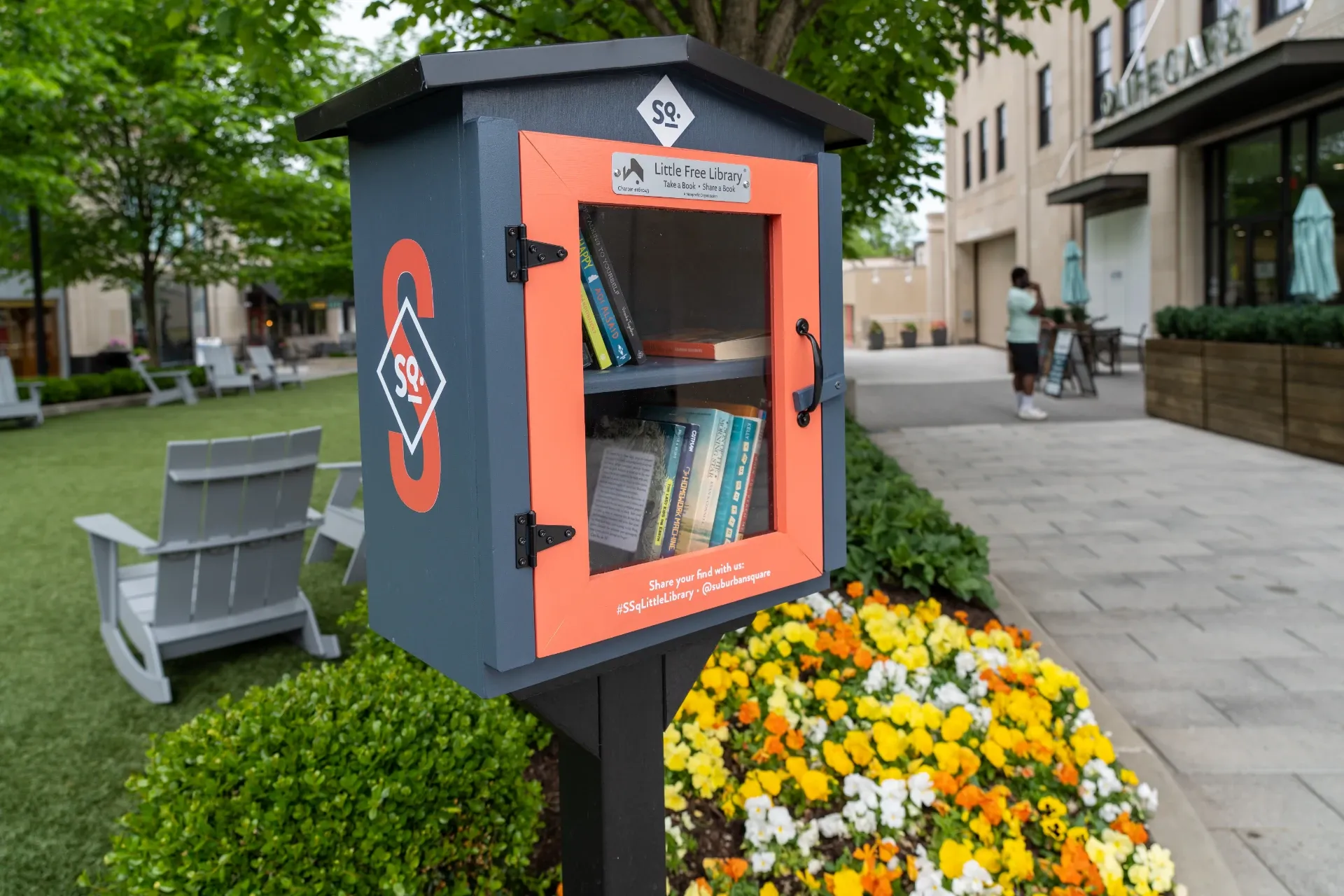 Little free library with lush landscaping and seating at Suburban Square
