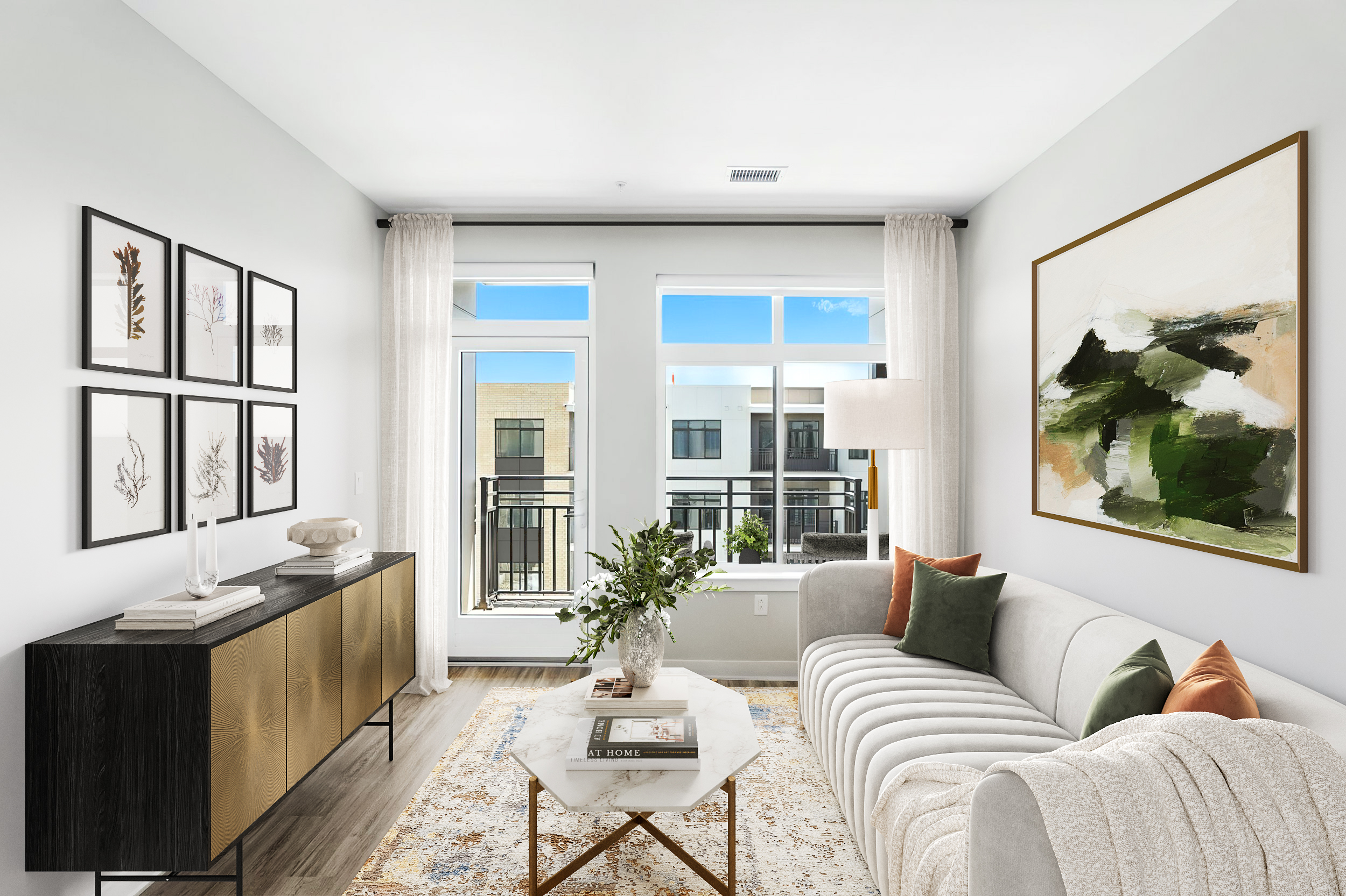 Living space with white couch, marble topped coffee table and gold finished console.
